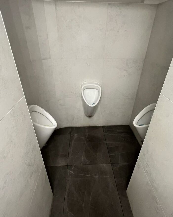 Three urinals installed in a small tiled bathroom with poor construction and design layout.