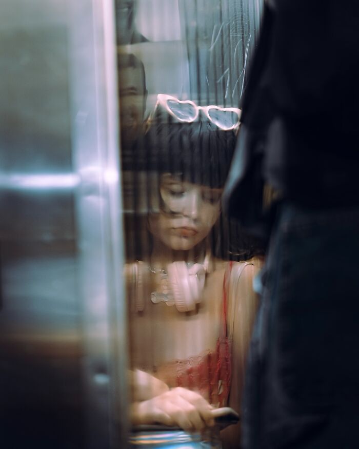 Blurred street photo of a woman with heart-shaped glasses and headphones, capturing a striking movie still vibe.