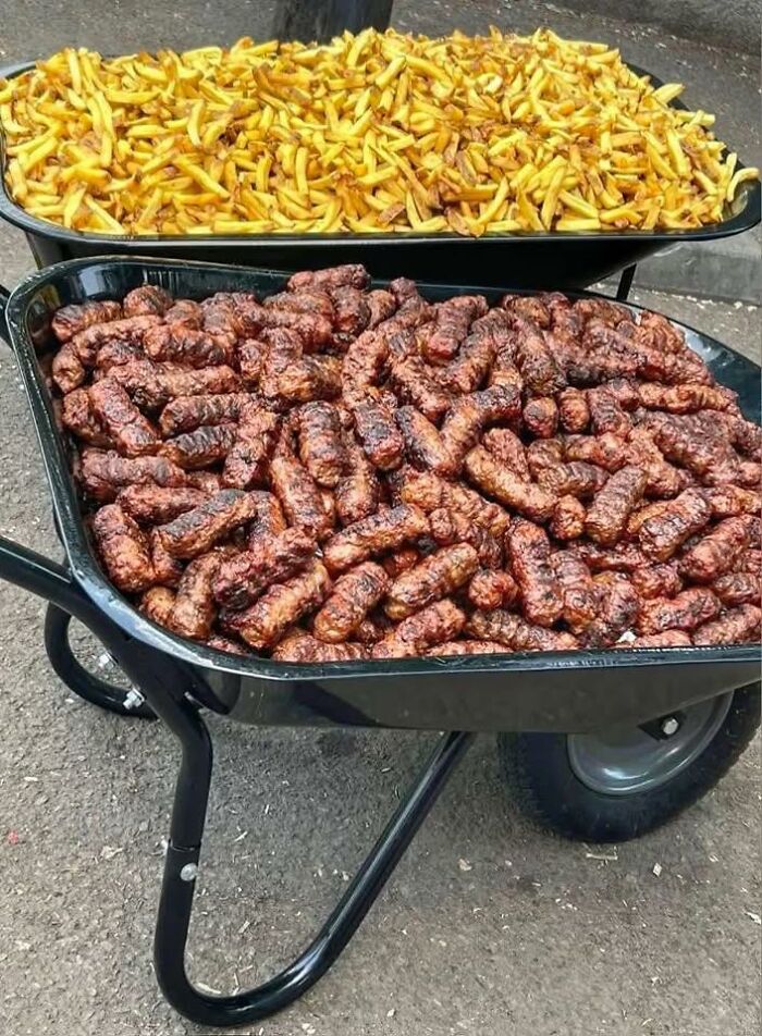 Two wheelbarrows filled with grilled sausages and fried potatoes, reflecting Eastern Europe food culture.