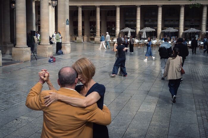 Couple dancing closely on a city street surrounded by pedestrians in striking street photos that feel like movie stills.