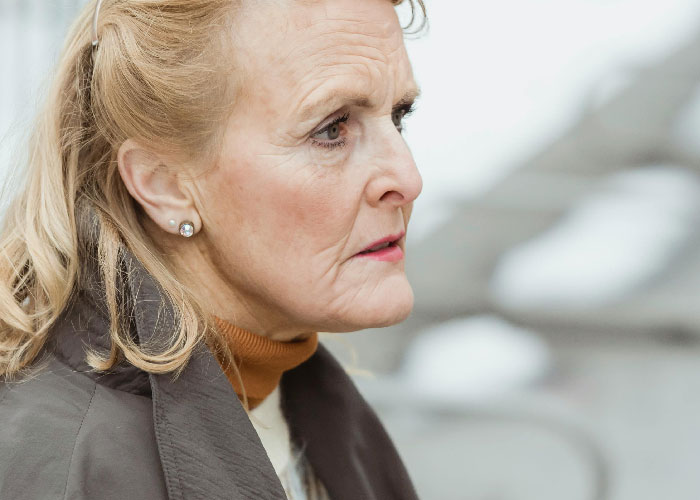 Elderly woman with a concerned expression outdoors, illustrating emotions related to mother poisoned me situation.