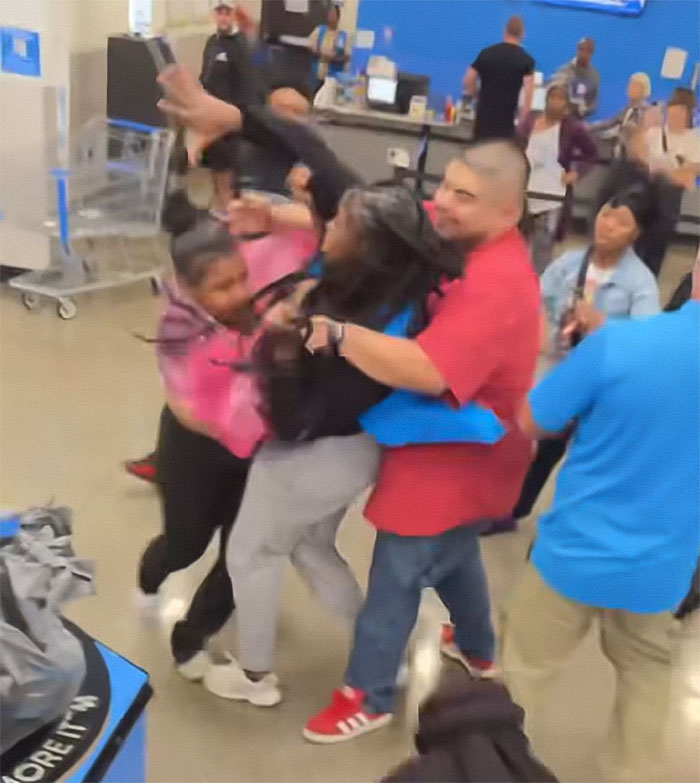 Crowd physically confronting Walmart employee during chaotic altercation inside the store with an angry mob ambush.