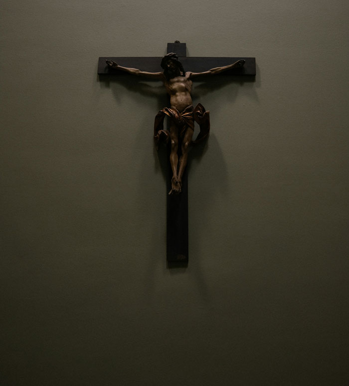 Dark wooden crucifix depicting Jesus on the cross, evoking somber and intense emotions related to horrible things witnessed.