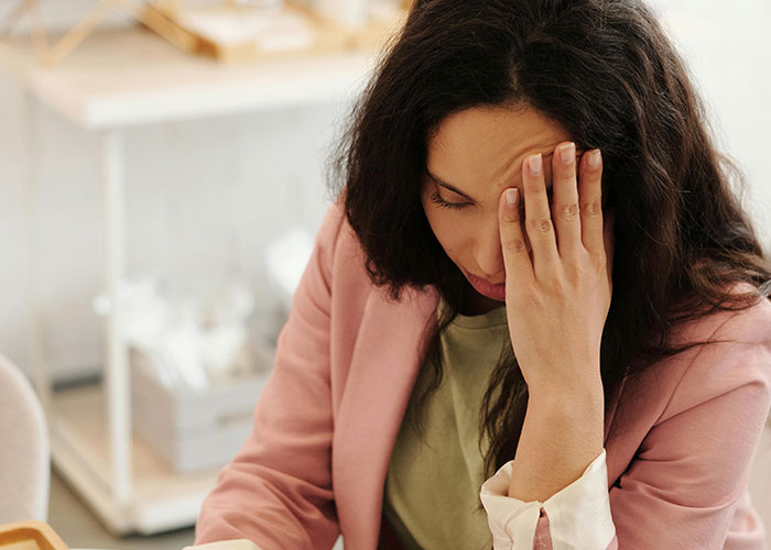 Woman in a pink blazer with hand on face, appearing surprised by incredible coincidences that seem too true to be fake.