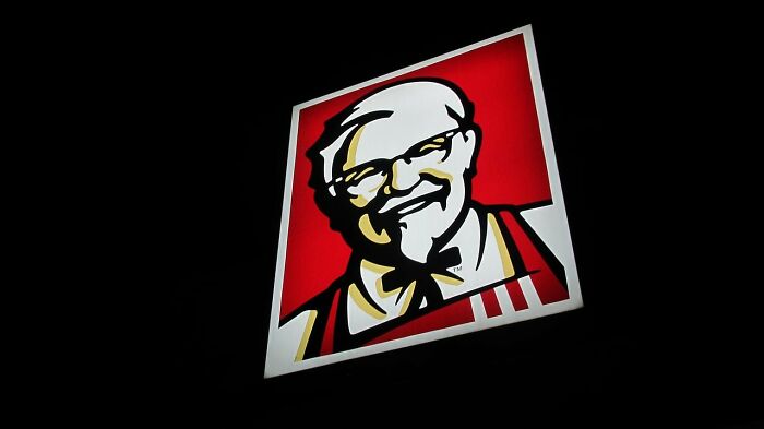 KFC logo illuminated at night, symbolizing food delivery drivers sharing chaotic and memorable stories.