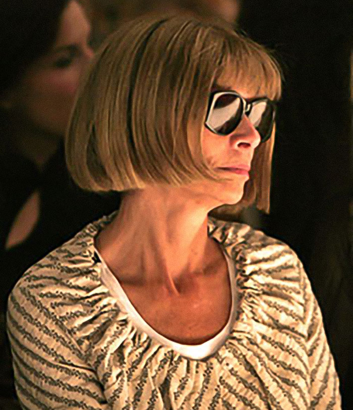 Anna Wintour wearing sunglasses and a patterned top, attending an event with a focused and composed expression.