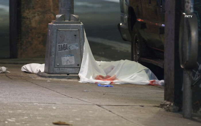 Covered body lies on a blood-stained city sidewalk near a vehicle, related to maniac driver shocking response incident. Covered body lies on a blood-stained city sidewalk near a vehicle, related to maniac driver shocking response incident.