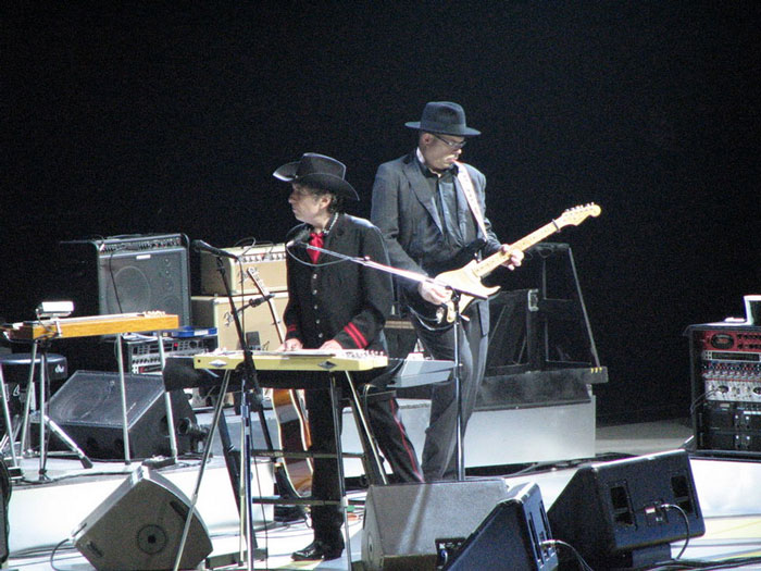 Two musicians wearing hats perform on stage with guitar and keyboard during a concert fans wish they'd skipped.
