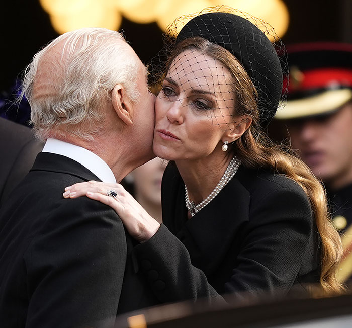 Kate Middleton kindly says goodbye to King Charles with a kiss on the cheek after royal funeral, both in mourning attire.