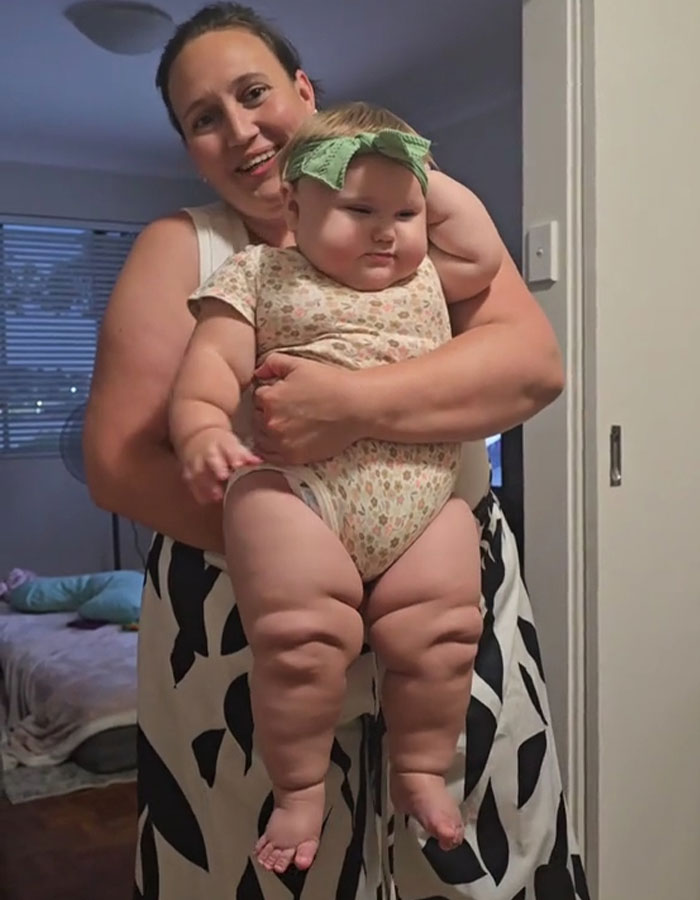 Woman holding giant baby with chubby legs indoors, highlighting rise in giant baby births and related health concerns. Woman holding giant baby with chubby legs indoors, highlighting rise in giant baby births and related health concerns.