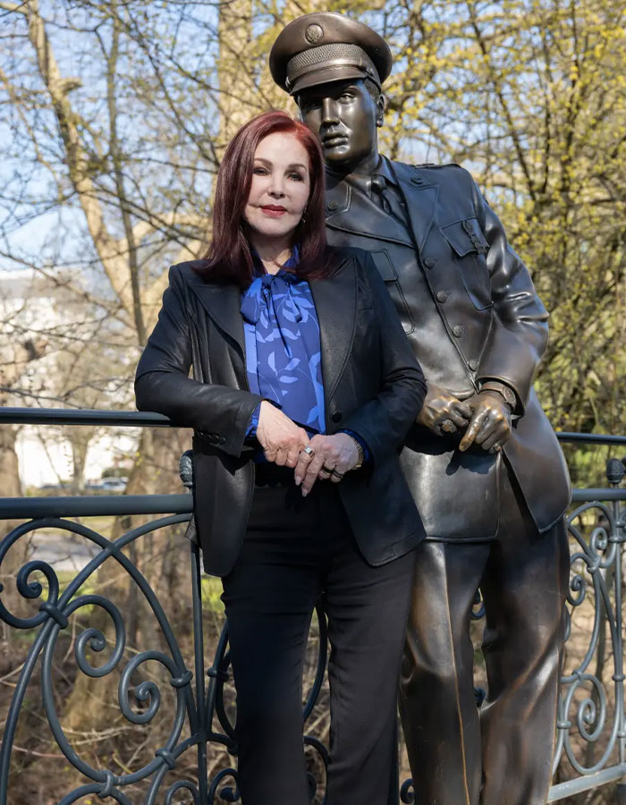 Priscilla Presley standing outdoors beside a bronze statue, discussing Lisa Marie and Michael Jackson's intimate life.