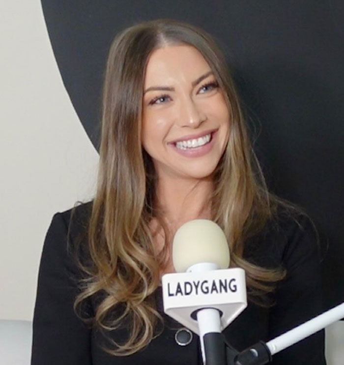 Reality TV star speaking into a LADYGANG microphone, smiling during an interview about Meghan Markle unappreciative comments.