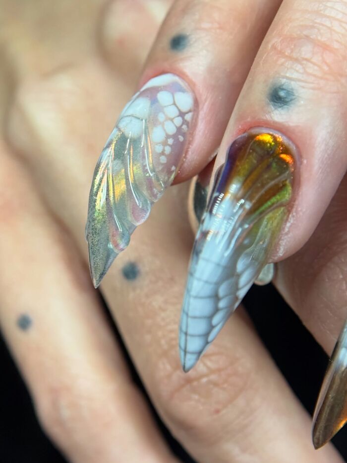 Unique nail designs with translucent butterfly wing patterns and unusual shapes creating an eye-catching look.