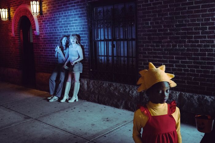 Street photo of three people at night, capturing cinematic lighting and mood like striking movie stills.