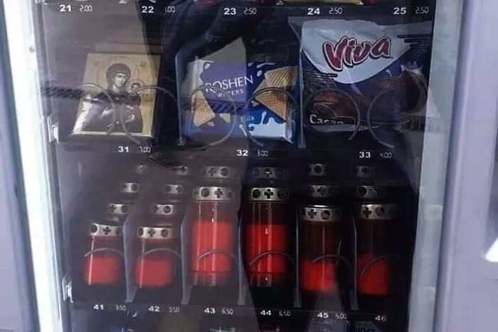Vending machine in Eastern Europe with religious icon, chocolates, and bottles filled with red liquid.