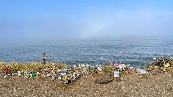 Memorial site with crosses, flowers, and trinkets by the ocean edge, symbolizing exact moments people knew they dated an idiot.