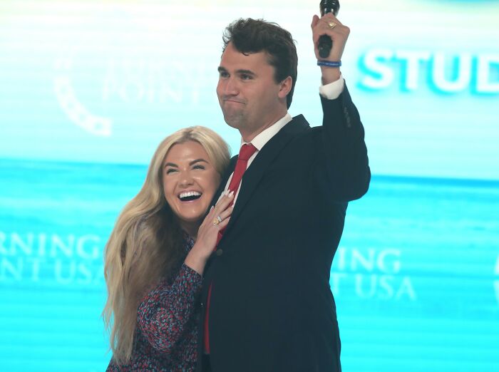 Erika Kirk smiling and holding a man in a suit raising a fist, capturing the gesture that sparked viral claim online.