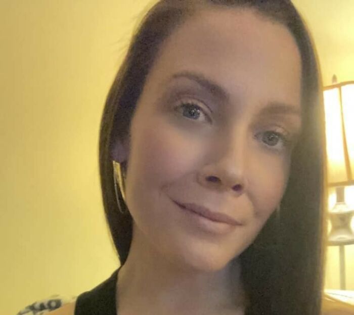 Woman with long dark hair and earrings in a softly lit room, related to school action against football player incident.