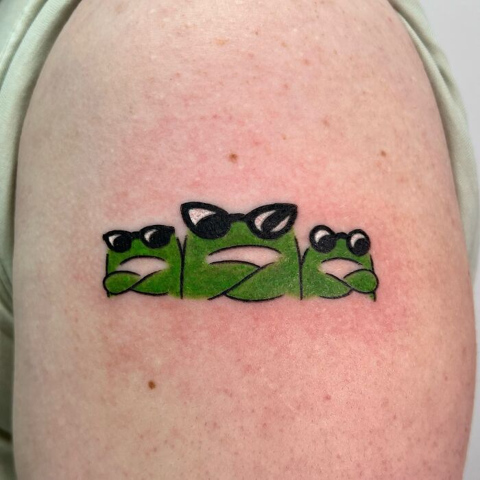 Small adorable frog tattoos wearing sunglasses, featuring a playful and minimalist animal design on the skin.