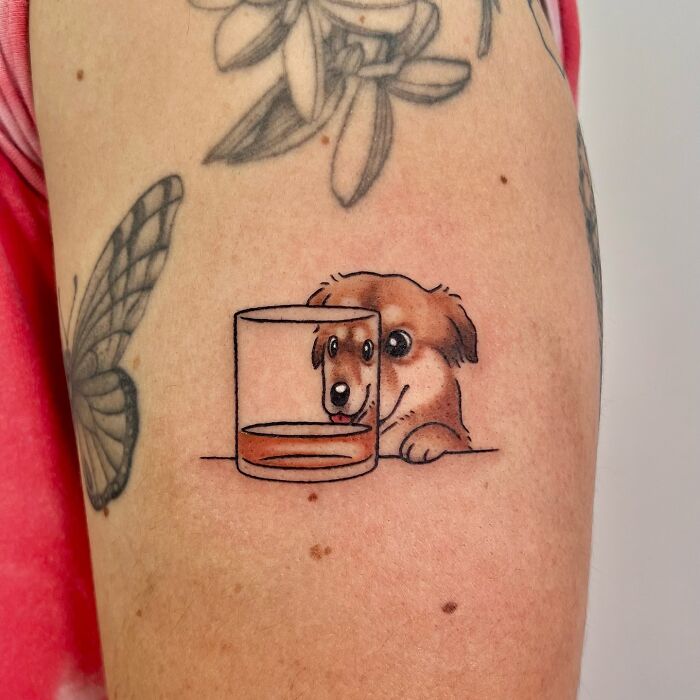 Cute animal tattoo of a dog looking through a glass on an arm, by Korean artist Buoy, showcasing adorable designs.
