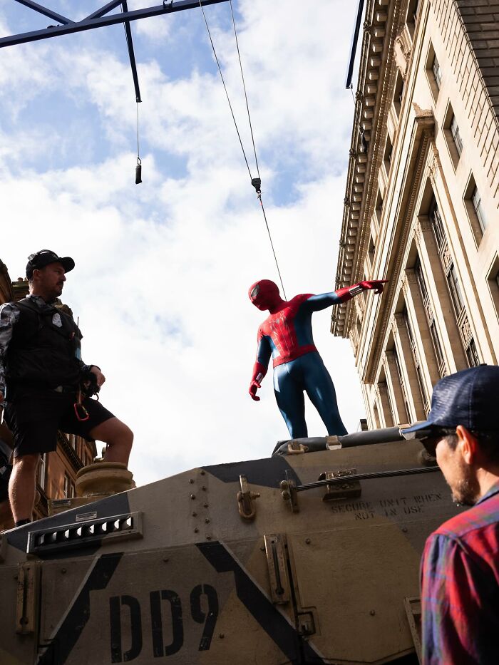 Spider-Man stunt with Tom Holland on set, harnessed and preparing for a head injury stunt in an urban filming location. Spider-Man stunt with Tom Holland on set, harnessed and preparing for a head injury stunt in an urban filming location.
