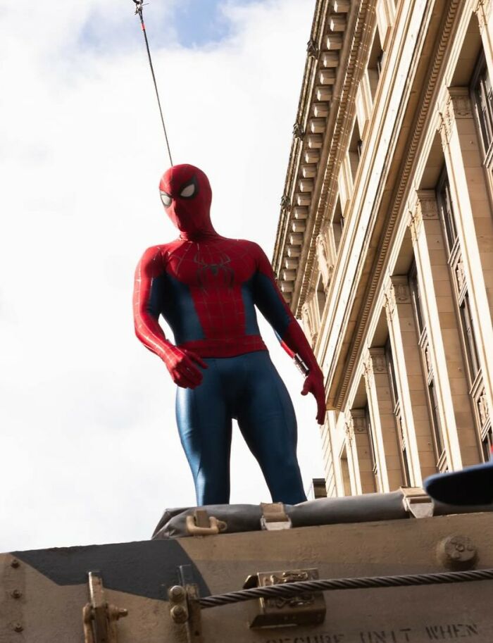Spider-Man stunt with actor suspended on a harness near a building, highlighting Tom Holland head injury incident. Spider-Man stunt with actor suspended on a harness near a building, highlighting Tom Holland head injury incident.