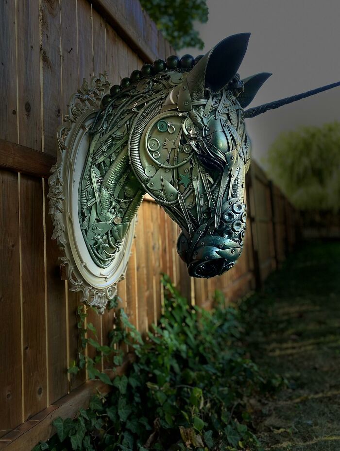 Recycled metal pieces crafted into a stunning animal sculpture mounted on a wooden fence outdoors.