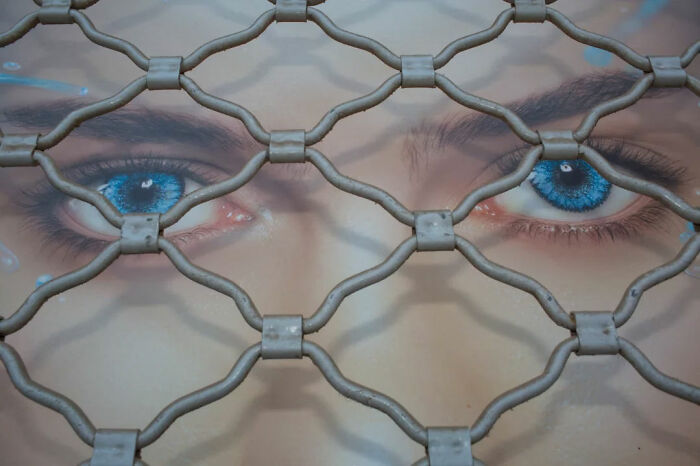 Close-up of blue eyes behind a metal grid, showcasing serendipitous moments captured in everyday life by a street photographer.