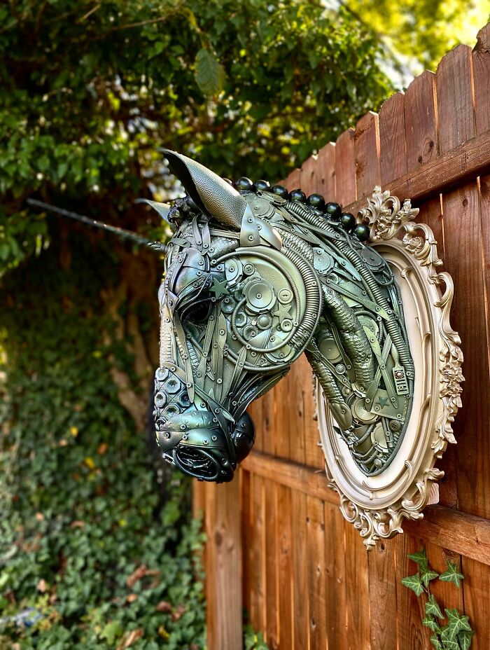 Recycled metal pieces crafted into a stunning animal sculpture mounted on a wooden fence outdoors.
