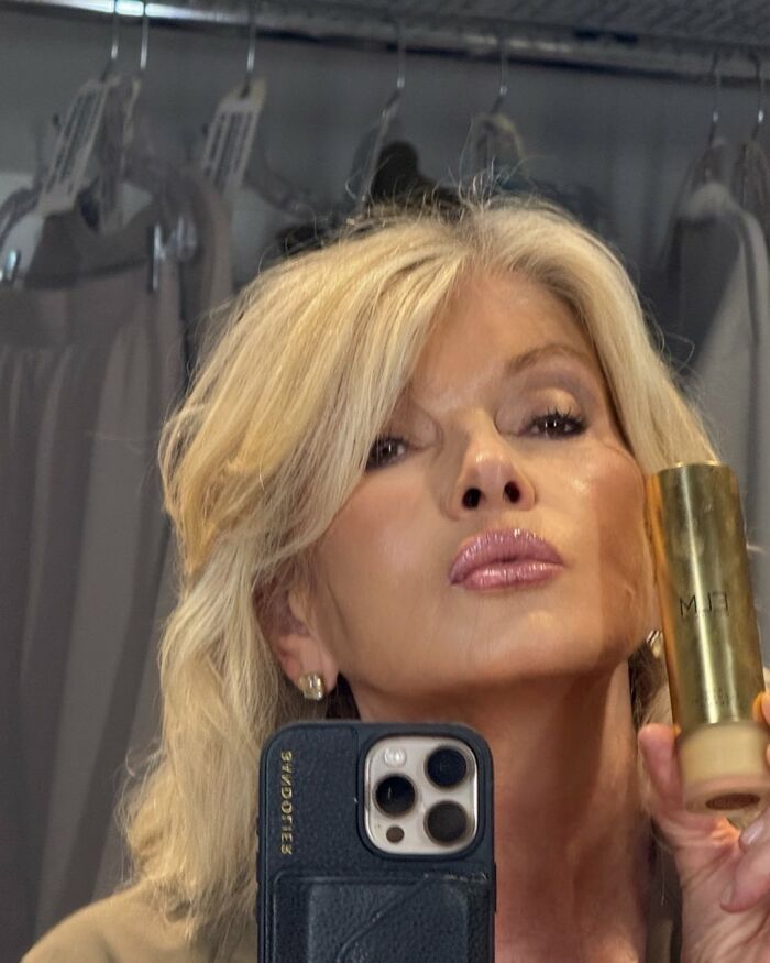 Martha Stewart taking a close-up selfie holding a gold cosmetic bottle, sparking plastic surgery rumors.