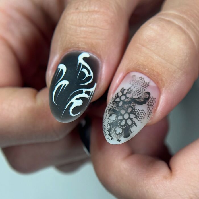 Black and white nail designs featuring intricate lace patterns and bold flame-like white accents on matte nails.