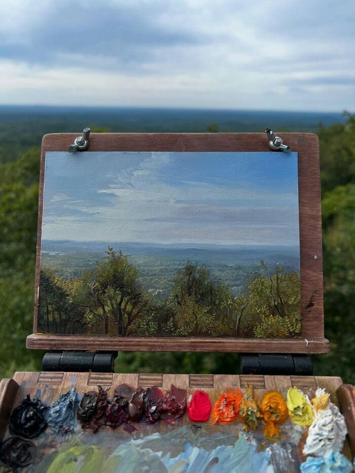 Outdoor painting setup showing detailed natural landscape artwork and colorful paint palette capturing the beauty of the natural world.