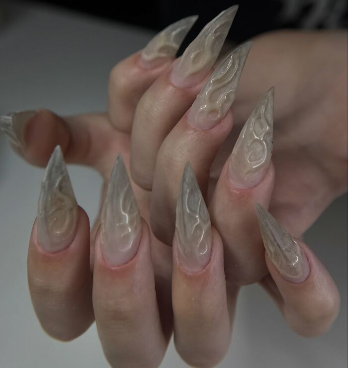 Long stiletto nail designs with translucent flame patterns creating a bold and unique nail art look.