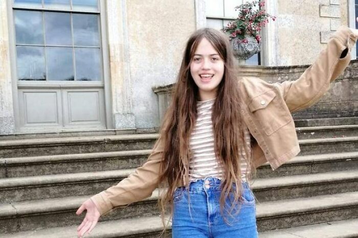 Teenage girl smiling and posing outside on stone steps, representing meningitis awareness and misdiagnosis risks.