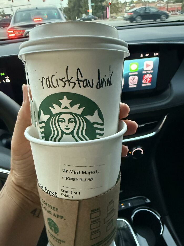 Starbucks cup held inside car showing hidden hate message written on Charlie Kirk's favorite drink cup.
