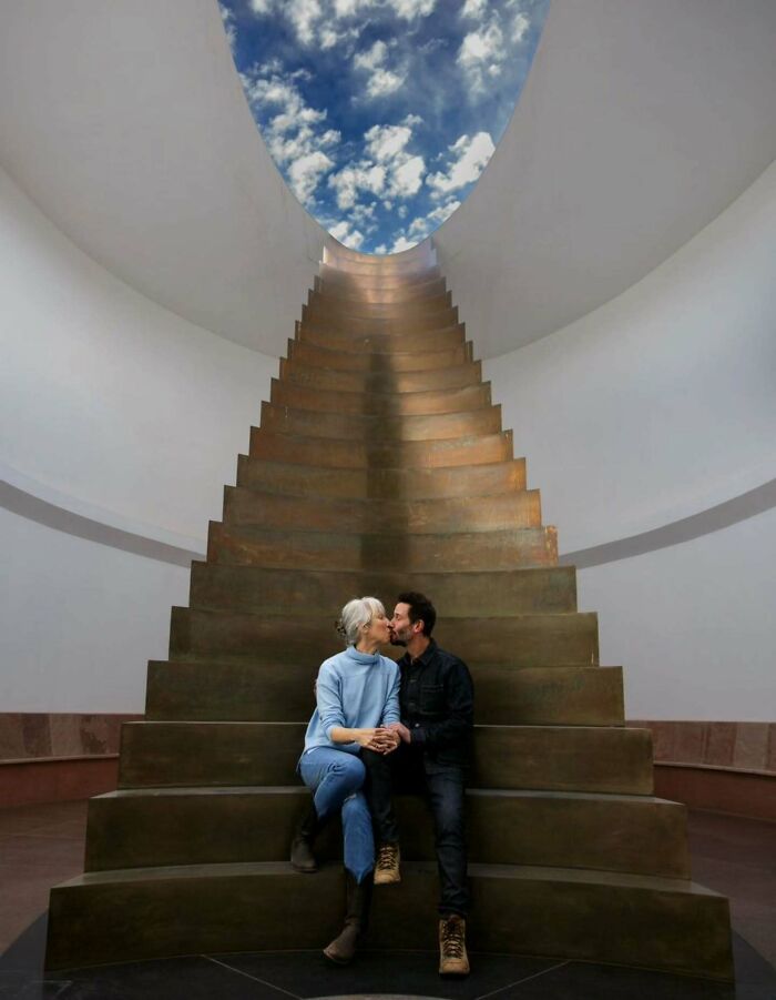 Couple sharing a kiss on large staircase under an open sky, highlighting Keanu Reeves girlfriend marriage rumors topic.