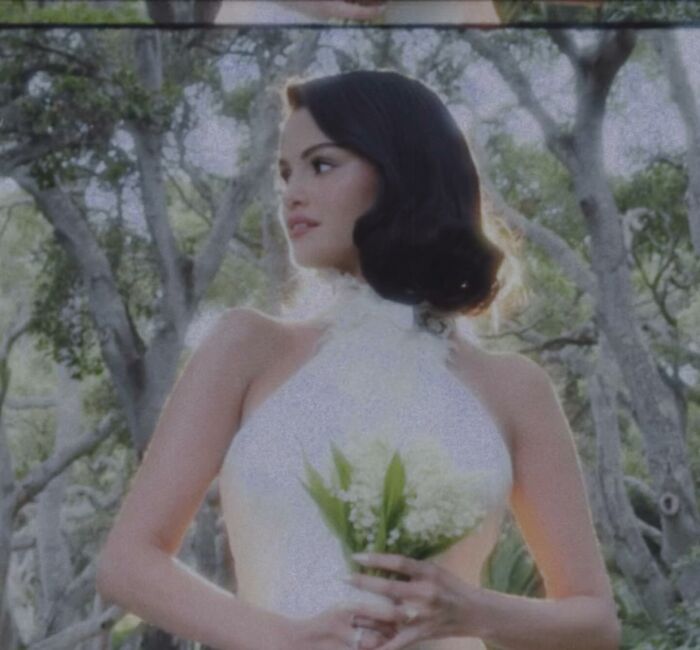 Selena Gomez in a white dress holding flowers outdoors, highlighting snubbing at her star-studded wedding. Selena Gomez in a white dress holding flowers outdoors, highlighting snubbing at her star-studded wedding.