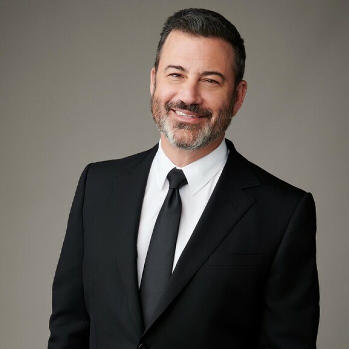 Jimmy Kimmel smiling in a black suit and tie, marking his return after show suspension over remarks controversy.
