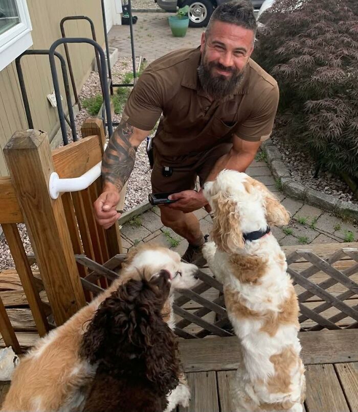 UPS driver smiling and interacting with three adorable pets at a wooden gate outside a home on a sunny day