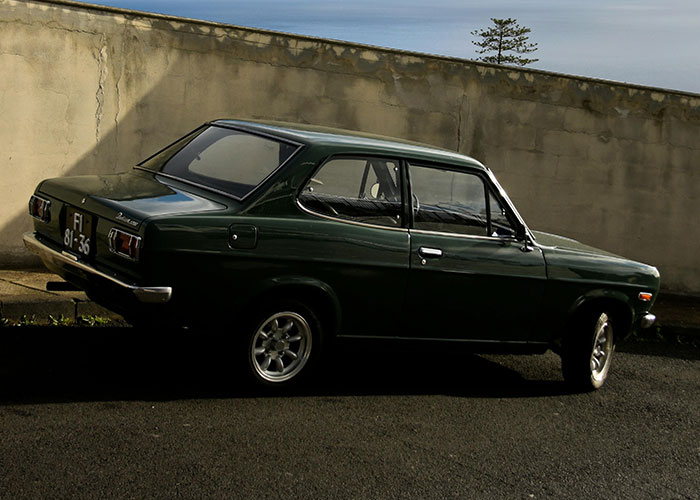 Dark green vintage car parked by a concrete wall, illustrating incredible coincidences that seem fake but are true.