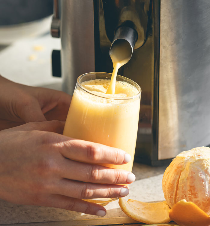 Person holding glass of fresh juice being poured from juicer, illustrating brilliant loopholes exploited.