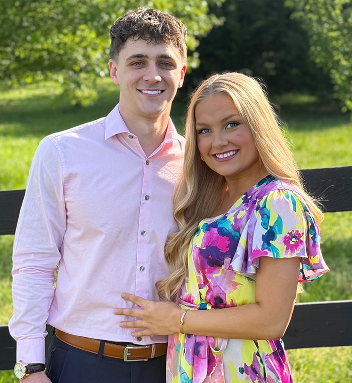 Young couple smiling outdoors in bright sunlight, related to cheerleader dropping out of university after newborn found in closet
