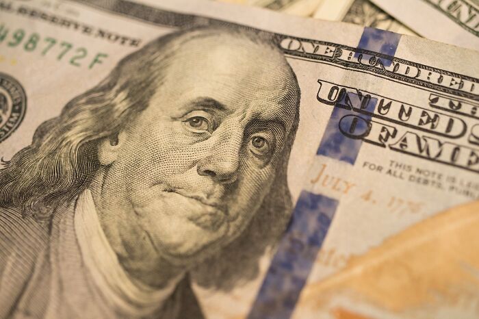 Close-up of Benjamin Franklin on a US hundred-dollar bill highlighting money related to food delivery driver tips.