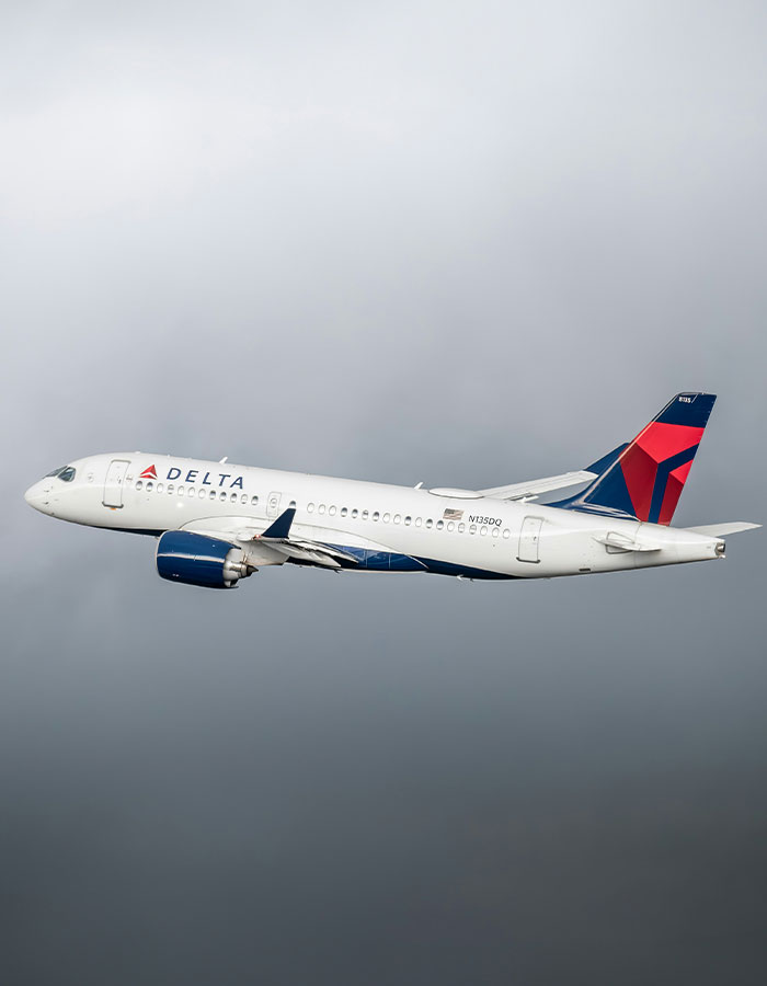 Delta airplane flying in cloudy sky, illustrating passenger attack on plus-size seatmate labeled too fat to fly incident. Delta airplane flying in cloudy sky, illustrating passenger attack on plus-size seatmate labeled too fat to fly incident.