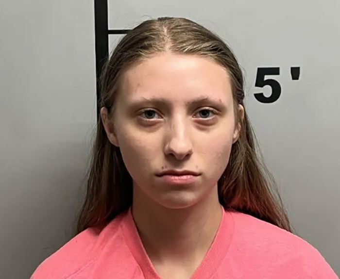 Young woman in front of height chart, related to sisters who destroyed Charlie Kirk memorial and became homeless.