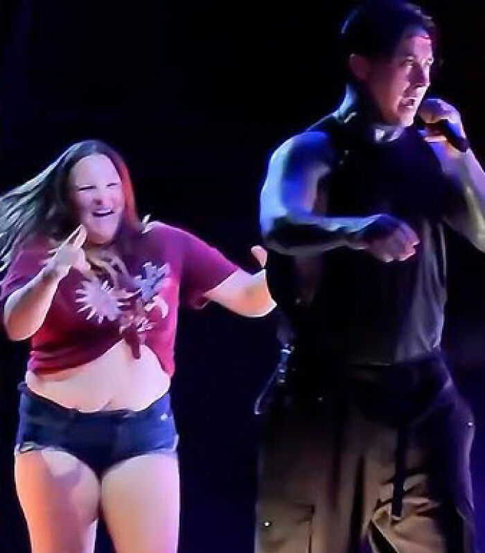 Ex-con rock star confronting woman who rushed the stage during a concert performance under bright lights.