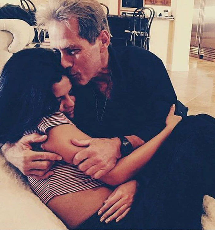 A man tenderly hugging a young woman indoors, capturing an intimate and emotional family moment. A man tenderly hugging a young woman indoors, capturing an intimate and emotional family moment.