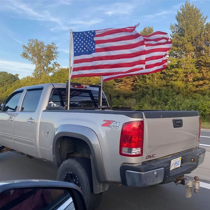 Silver GMC pickup truck on road with two American flags waving, related to Michigan suspect's eerie confession case.