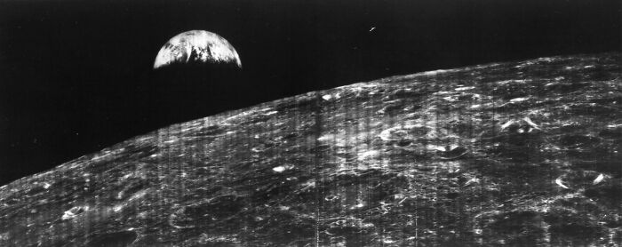 Black and white astronomy photo showing the moon's surface with Earth rising in the background, capturing space's mystery.