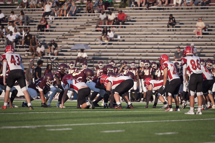 High school football players lined up on the field as school takes strong and decisive action after spine injury incident.